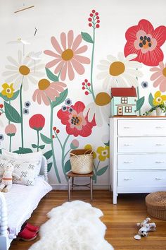 a child's bedroom with flowers painted on the wall and a white dresser next to it