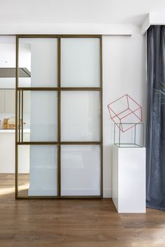 a white room with glass doors and a red sculpture