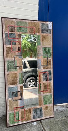 a car is reflected in a mirror on the side of a building near a blue door