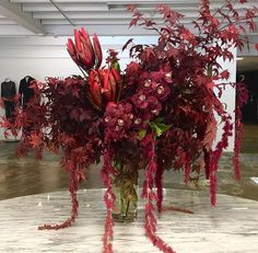 a vase filled with red flowers sitting on top of a marble table covered in water