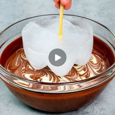 someone is dipping marshmallows into melted chocolate in a bowl with a toothpick