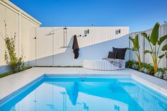 an empty pool in the middle of a white fenced area with plants and umbrellas