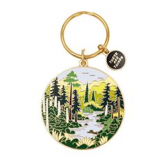 a round keychain with a lake and trees on the front, in gold tone