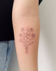 a woman with a tattoo on her arm holding a bouquet of flowers in front of her leg