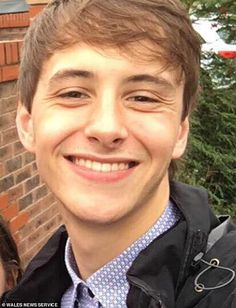 a smiling young man standing next to a woman in front of a red brick building