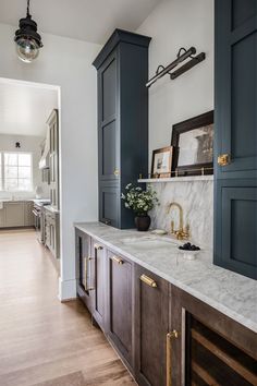 a kitchen with blue cabinets and marble counter tops, along with wood flooring that matches the white walls