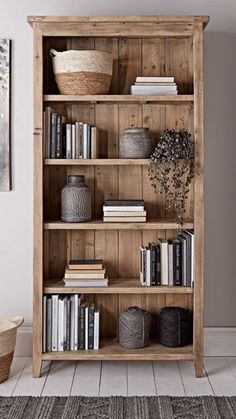 a wooden book shelf with books and baskets on top