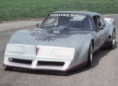 a silver car parked on top of a parking lot next to a grass covered field