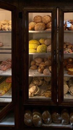 a display case filled with lots of different types of breads and pastries in glass doors