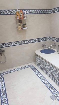 a bathroom with blue and white tiles on the floor, sink and shower head mounted to the wall