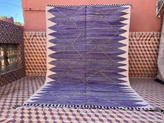 a purple and white rug sitting on top of a tiled floor next to a wall