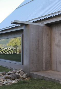 an outhouse with the reflection of a horse in it's window and rocks on the ground