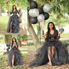 a woman in a black dress sitting under a tree holding a cake and some balloons