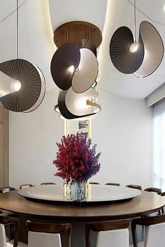 a dining room table with chairs and lights hanging from the ceiling