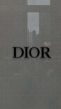 the word dior is displayed in front of a window with skyscrapers behind it