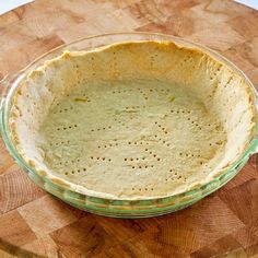 an uncooked pie crust in a glass dish on top of a wooden table