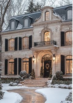 a large white house with black shutters in the snow