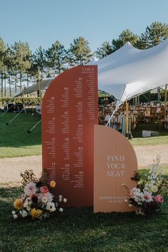 an outdoor seating area with flowers on the grass and a sign that says find your seat