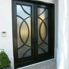 a black double door with glass panels and potted plants