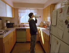 a man standing in a kitchen next to a refrigerator