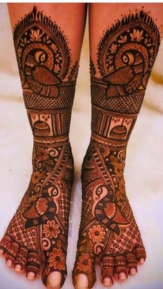 the legs and feet of a woman with henna tattoos on their feet, decorated with flowers