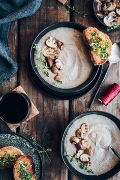 two plates filled with soup and mushrooms on top of a wooden table