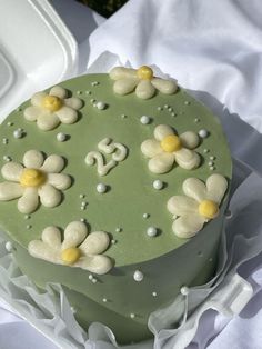 a green cake with white and yellow flowers on it