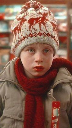 a young boy wearing a red and white knitted hat, scarf and mittens