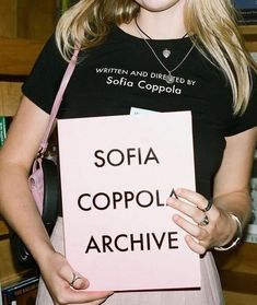 a woman holding a sign that says sofia coppola archive