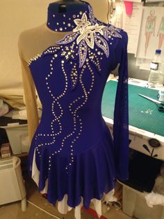 a purple and white dress on display in front of a sewing machine with lots of beading