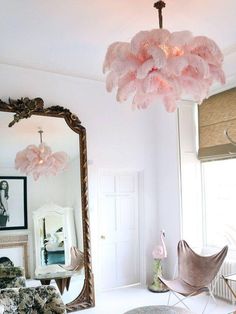 a pink chandelier hanging from the ceiling in a room with mirrors and furniture