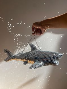 a hand holding a chain that is attached to a shark ornament