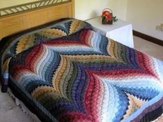 a bed covered in a multicolored quilt next to a nightstand