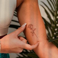 a woman's arm with a small flower tattoo on the left side of her arm