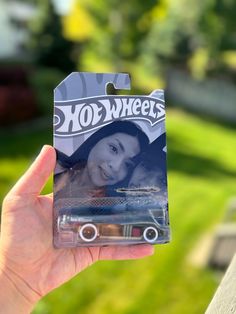 a person holding up a toy car in front of their face and it's packaging