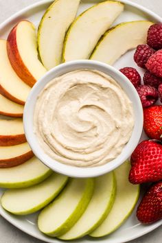 a plate with apples, strawberries and an apple dip