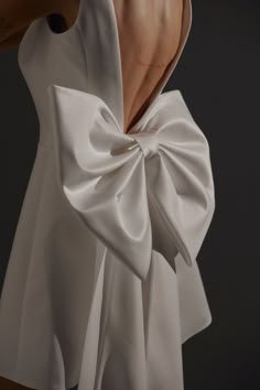 the back of a woman's white dress with a large bow