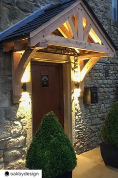 the front entrance to a stone building with potted plants and lights on it's side