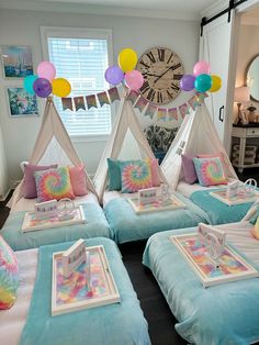 a room filled with lots of beds covered in pillows and blankets next to a clock