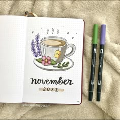 an open notebook with a cup of coffee and two markers