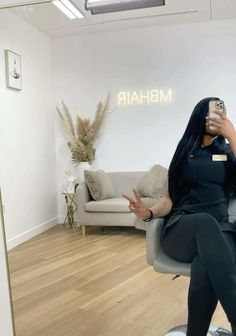 a woman sitting in a chair taking a selfie with her cell phone while wearing black tights