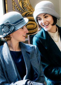 two women sitting next to each other wearing hats