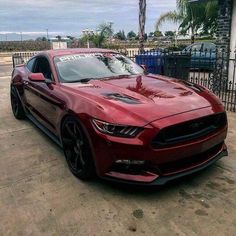 a red mustang parked in front of a house