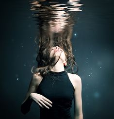 a woman is floating in the water with her hair blowing