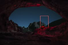 an opening in the side of a cave at night with red light coming from it