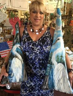 a woman in a blue and white dress is holding two large bird wings