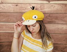 a woman wearing a yellow and white striped shirt with a crocheted bird hat on her head