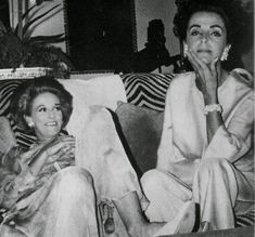 black and white photograph of two women sitting next to each other on a couch in a living room