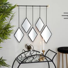 a table with a candle and some mirrors hanging on it's wall next to a potted plant