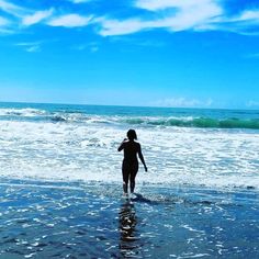 a woman is walking in the water at the beach